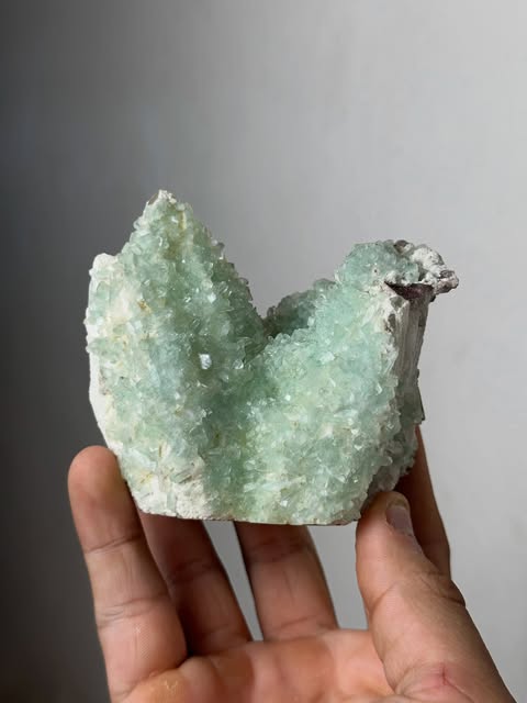 Pale green crystal specimen held in a hand